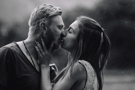 beautiful couple kissing outside in the rainの写真素材