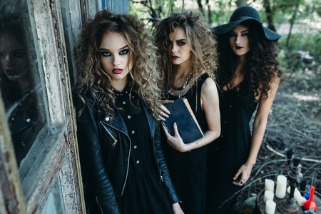 three vintage women as witches, poses near an abandoned building on the eve of Halloweenの写真素材