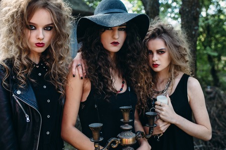three vintage women as witches, pose in front of an abandoned building on the eve of Halloweenの写真素材