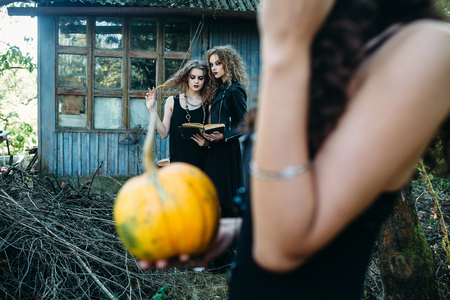 three vintage women as witches, pose in front of an abandoned building on the eve of Halloweenの写真素材