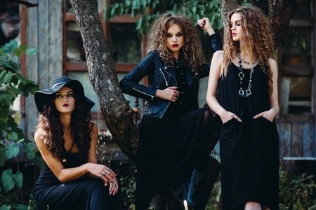 three vintage women as witches, pose in front of an abandoned building on the eve of Halloweenの写真素材
