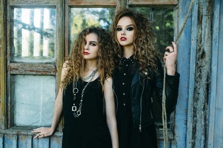 two vintage women as witches, posing beside an abandoned building on the eve of Halloweenの写真素材