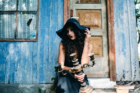 Vintage woman as witch, posing against the backdrop of an abandoned place on the eve of Halloweenの写真素材