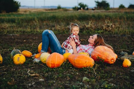 mother and daughter lie between pumpkins on the fieldの写真素材