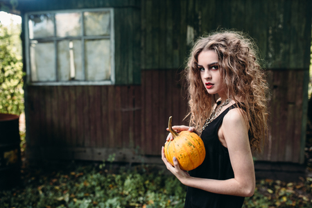 Vintage woman as witch, posing against the backdrop of an abandoned place on the eve of Halloweenの写真素材
