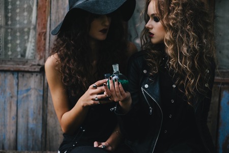 Two vintage witches perform magic ritual, with elixir in hand on the eve of Halloweenの写真素材