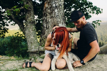 beautiful couple and a dog have a rest near a treeの写真素材