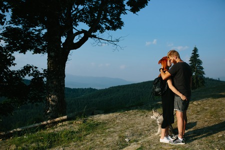 beautiful couple standing on a hill and gently hugging each otherの写真素材