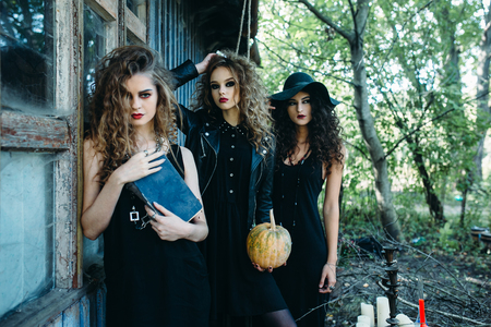 three vintage women as witches, poses near an abandoned building on the eve of Halloweenの写真素材