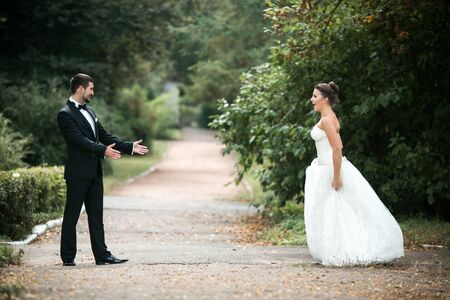 Beautiful wedding couple standing opposite each other in the parkの写真素材