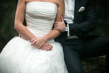 Beautiful wedding couple sitting in the woods on a fallen treeの写真素材