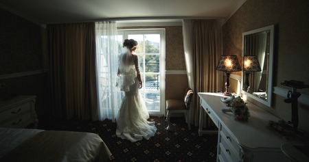 bride looking through the window from the hotel roomの写真素材