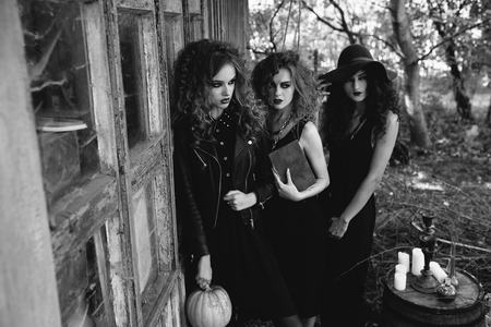 three vintage women as witches, poses near an abandoned building on the eve of Halloweenの写真素材