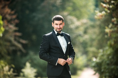 confident groom posing for the camera in the parkの写真素材
