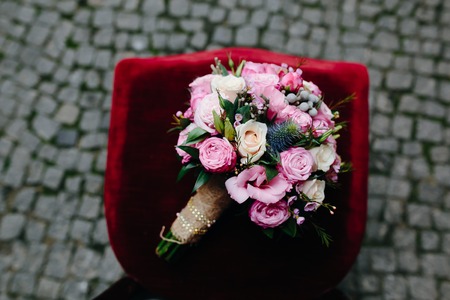 Wedding bouquet with roses on a red chairの写真素材
