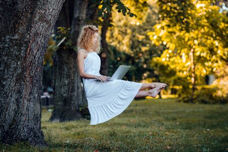 beautiful girl levitates in nature with laptopの写真素材