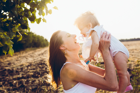 mother playing with his little daughter on the farmの写真素材