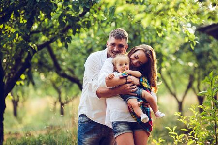 dad, mom and little girl on the farm on a background of trees