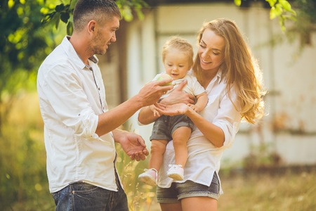 Parents with baby enjoying picnic on a farm with apple and cherry trees.の写真素材