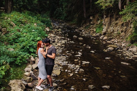 beautiful couple hugging each other near a mountain river