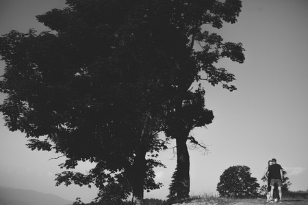 beautiful couple standing on a hill and gently hugging each otherの写真素材