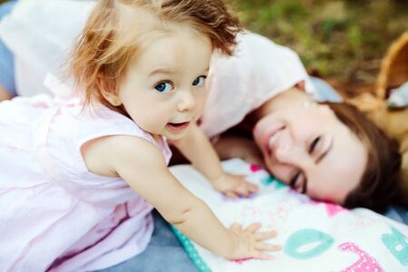 Having fun. Pretty young mother and her little daughter lying on cover in park and having picnic.の写真素材