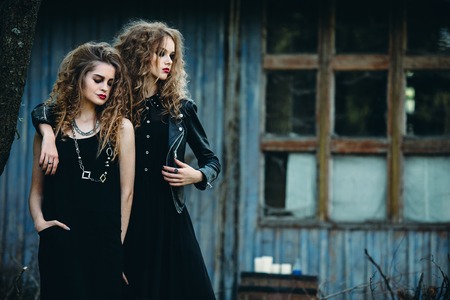 two vintage women as witches, posing beside an abandoned building on the eve of Halloweenの写真素材
