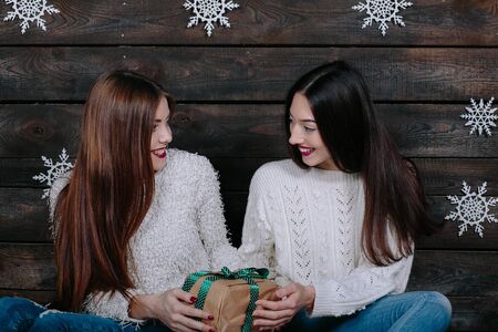 Two pretty young funny girls friends smiling and having fun, holding holiday presentsの写真素材
