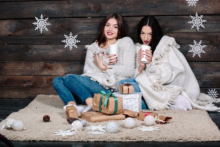 Two pretty young funny girls friends hugs smiling and cuddle togetherの写真素材