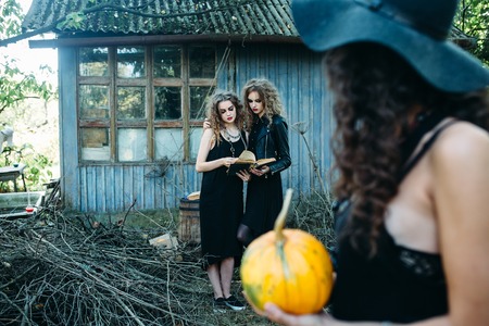 three vintage women as witches, pose in front of an abandoned building on the eve of Halloweenの写真素材