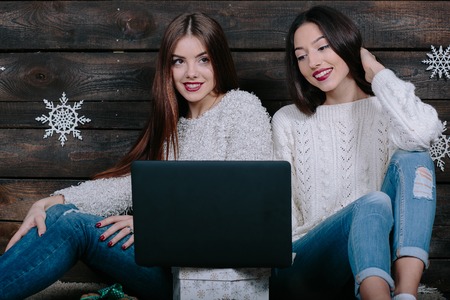Two beautiful girls siting on the floor with a laptop, between gifts for Christmasの写真素材