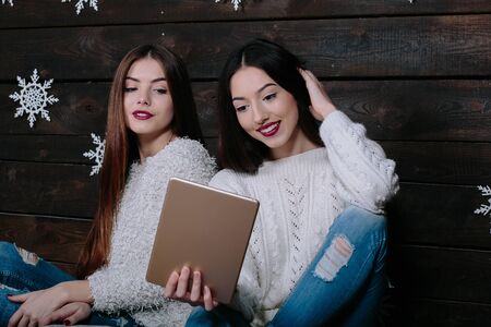 Two beautiful girls sitting on the floor with a tablet, between gifts for Christmasの写真素材