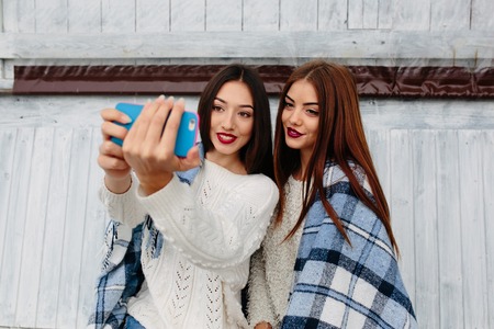 Two girls sit on the bench and do selfieの写真素材