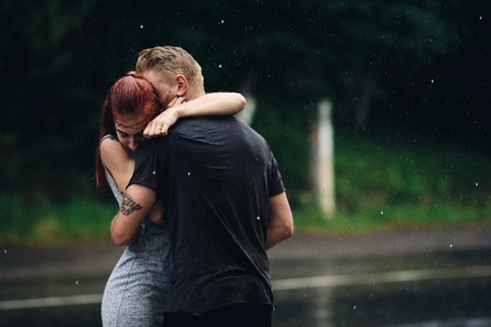 beautiful couple hugging on outside in the rainの写真素材