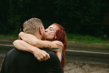 beautiful couple kissing outside in the rainの写真素材