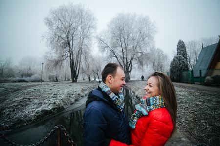beautiful couple is standing on a small bridge in a winter parkの写真素材