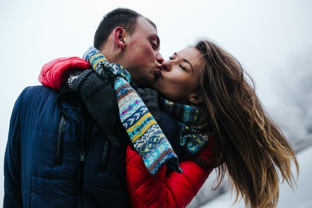 Young beautiful couple having fun in the snow-covered parkの写真素材