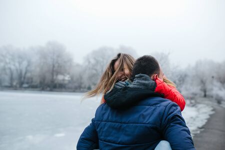 Young beautiful couple having fun in the snow-covered parkの写真素材
