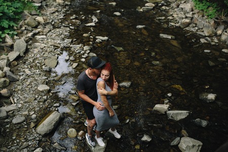 beautiful couple hugging each other near a mountain riverの写真素材