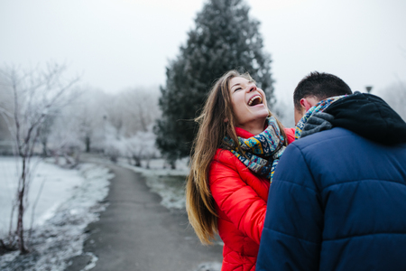 Young beautiful couple having fun in the snow-covered parkの写真素材
