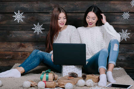 Two beautiful girls siting on the floor with a laptop, between gifts for Christmasの写真素材