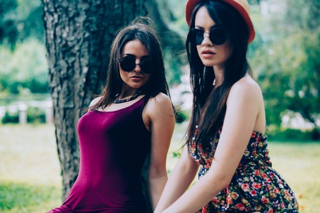 Two young beautiful girls sitting in the park