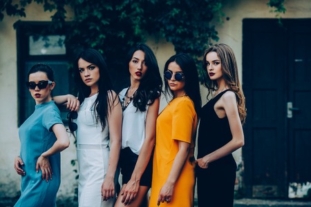 Five beautiful young girls in dresses posing in front of houseの写真素材