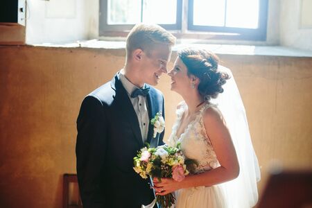 Bride and groom posing on the background of a large window