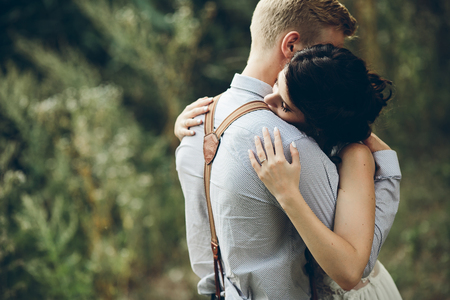groom gently embracing his bride in the forestの写真素材