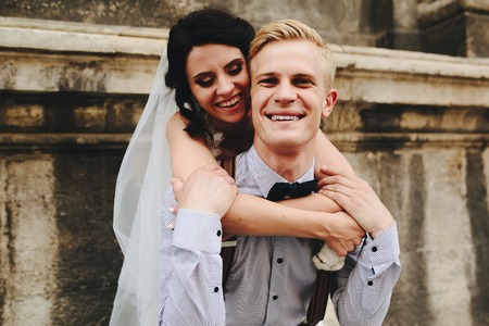 groom carries bride on his back, outdoorsの写真素材