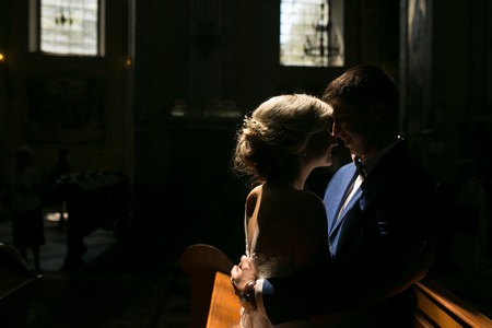 bride and groom sitting on a bench in a dark room illuminated by lightの写真素材