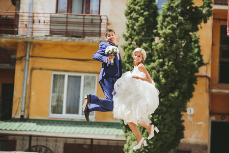 Happy just married couple jumping on the streetの写真素材