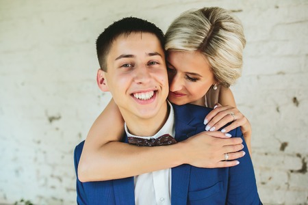 Bride embraces bridegroom, couple stands near the old houseの写真素材