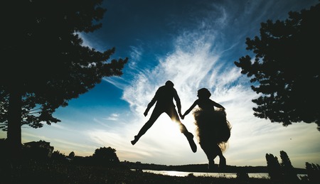 groom and bride jumping against the beautiful sky, silhouettesの写真素材